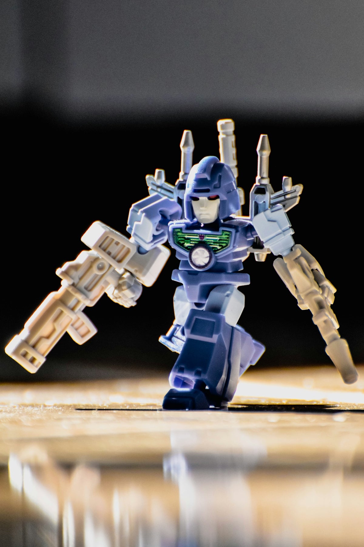 A small blue robot holding two guns