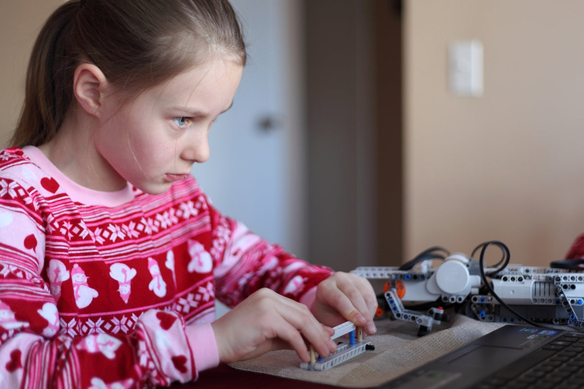 Young girl concentrating on assembling a construction toy.