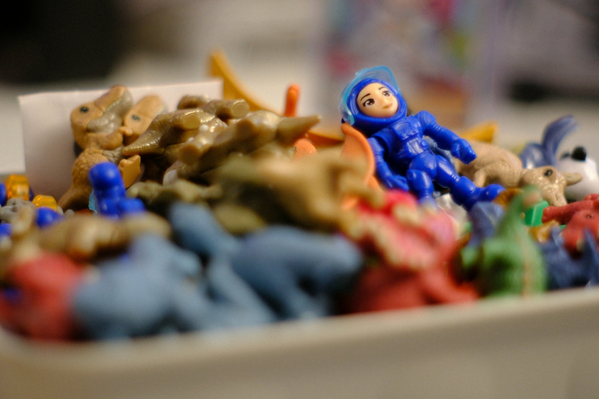 A blue astronaut toy among many colorful small toys.
