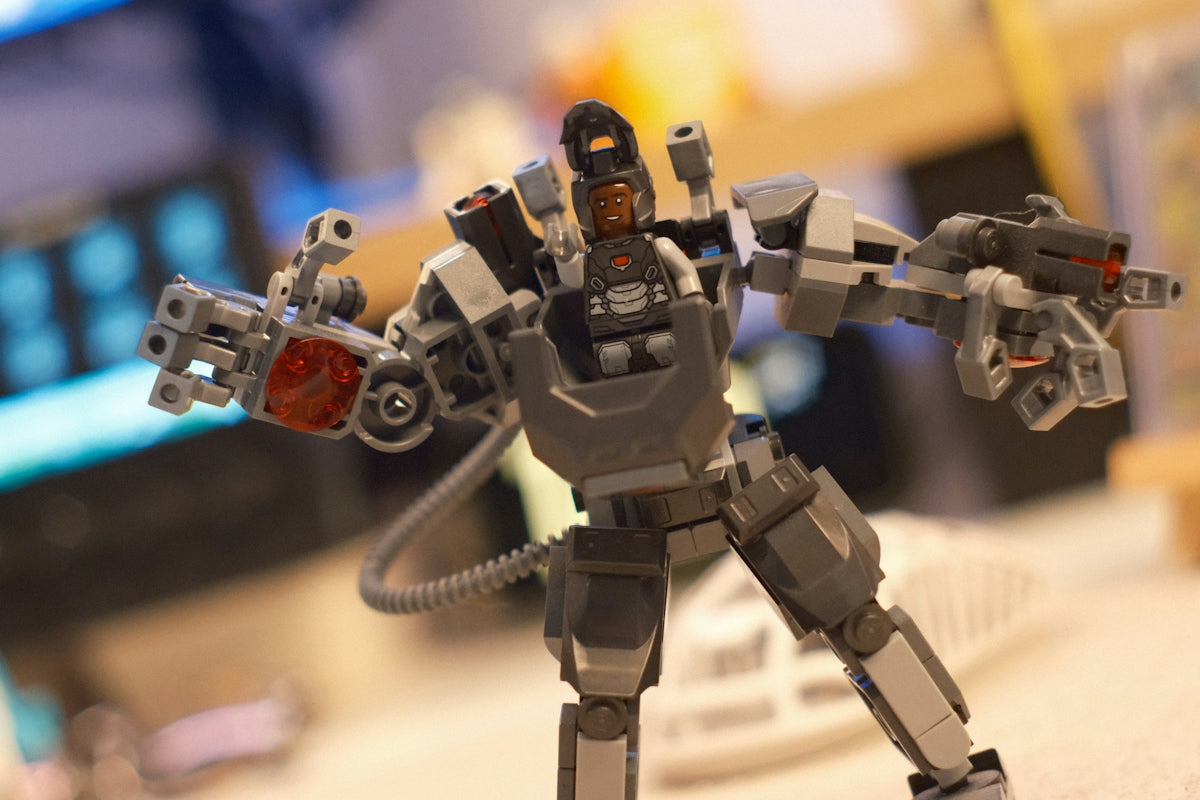 A lego robot figure standing on a desk with weapons.