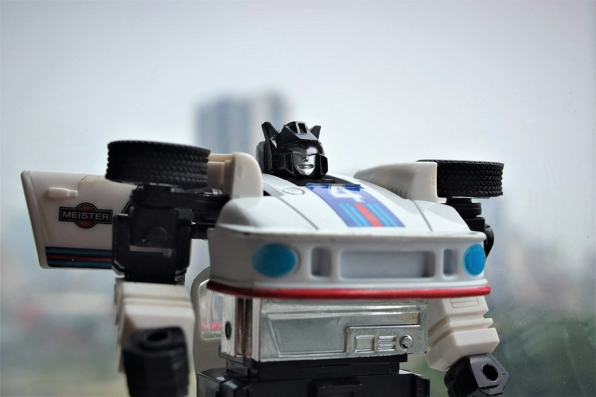 A white robot car toy with blue and red stripes.
